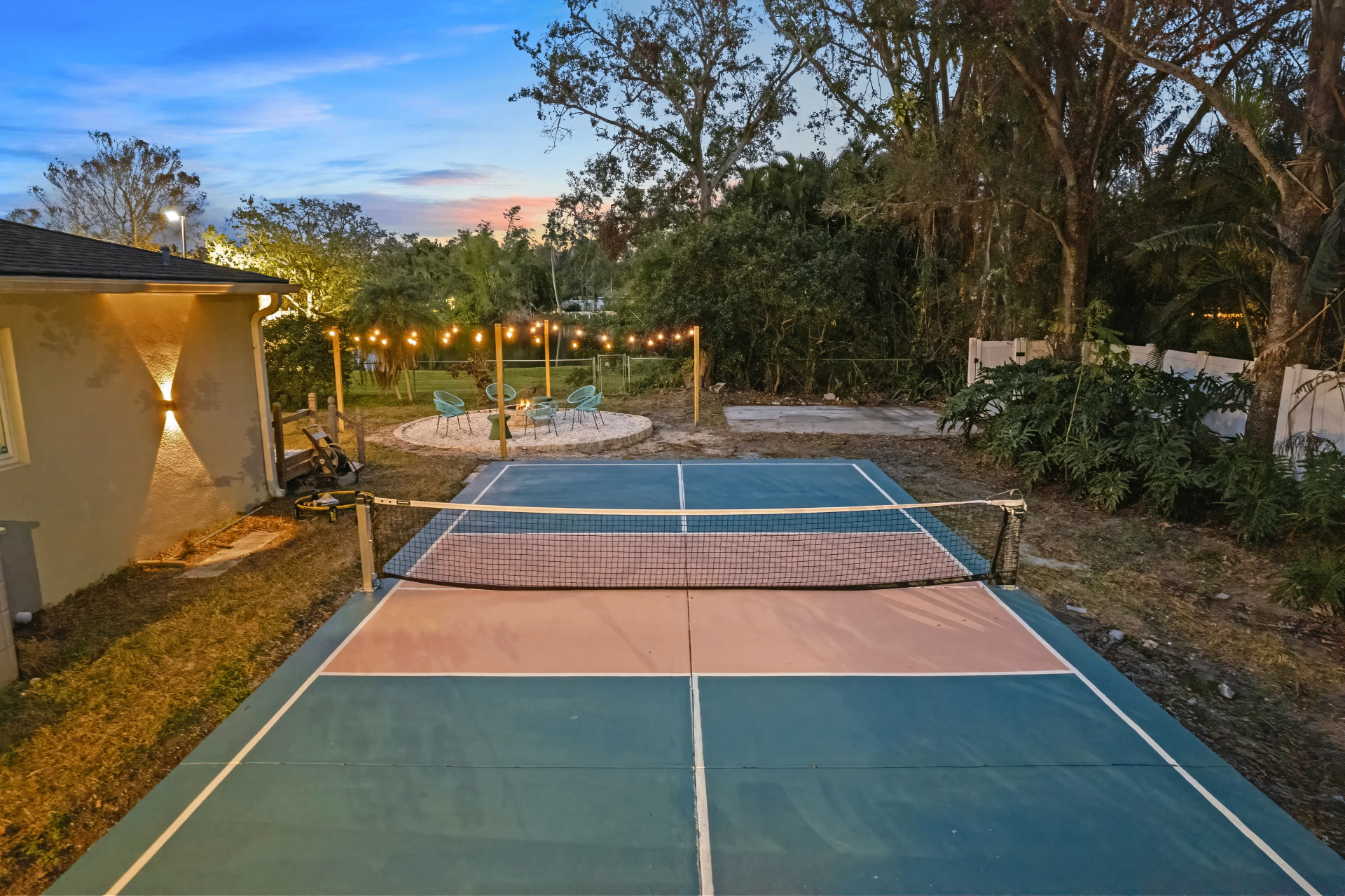 Private pickleball court and cozy firepit lounge area surrounded by lush greenery